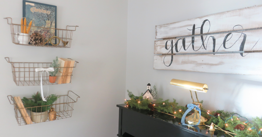 Top of piano with greenery and gather sign with three baskets decorated for Christmas