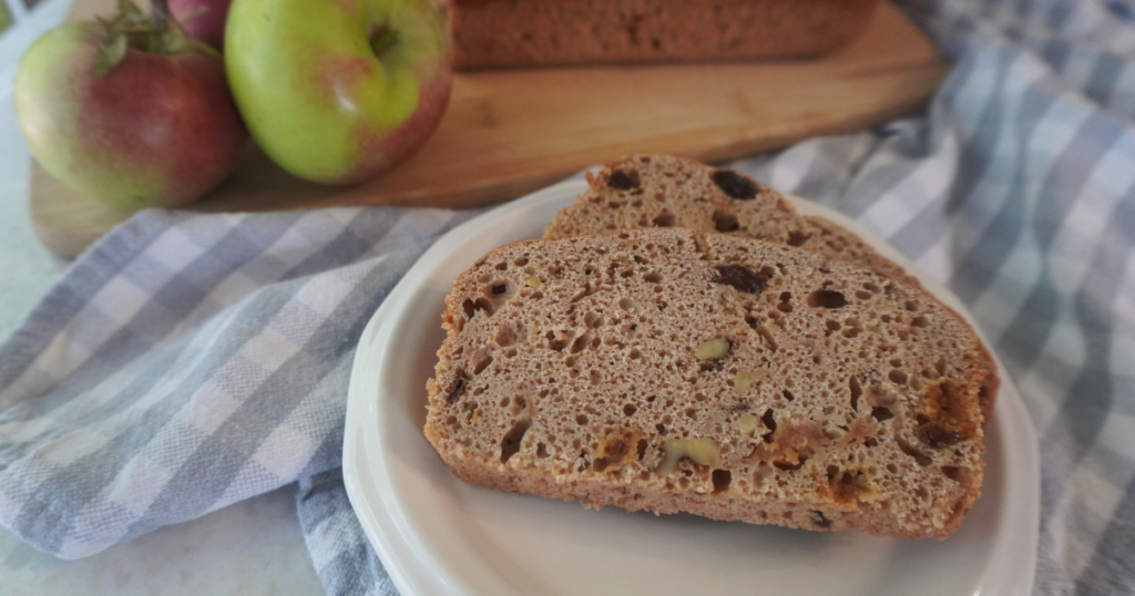 2 slices of sourdough bread on plate with side view of apples and partial bread