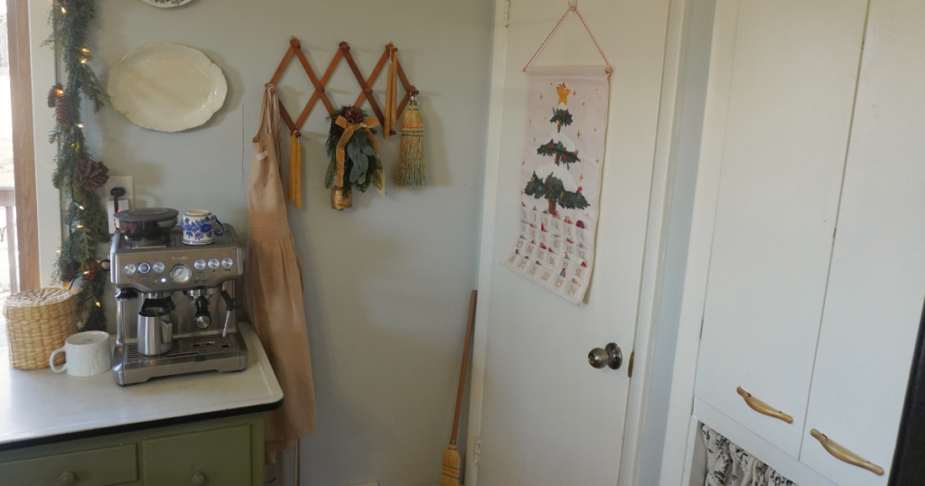 Door with advent calendar. Accordian rack with greenery and candles. Coffee station to left of that.