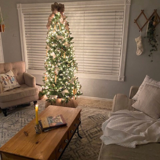 Christmas tree lit up with candle on coffee table and white stocking on accordian rack.