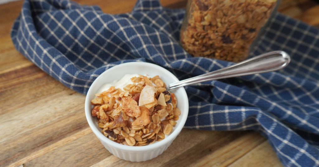 bowl of yogurt with granola on top and jar of granola in background.