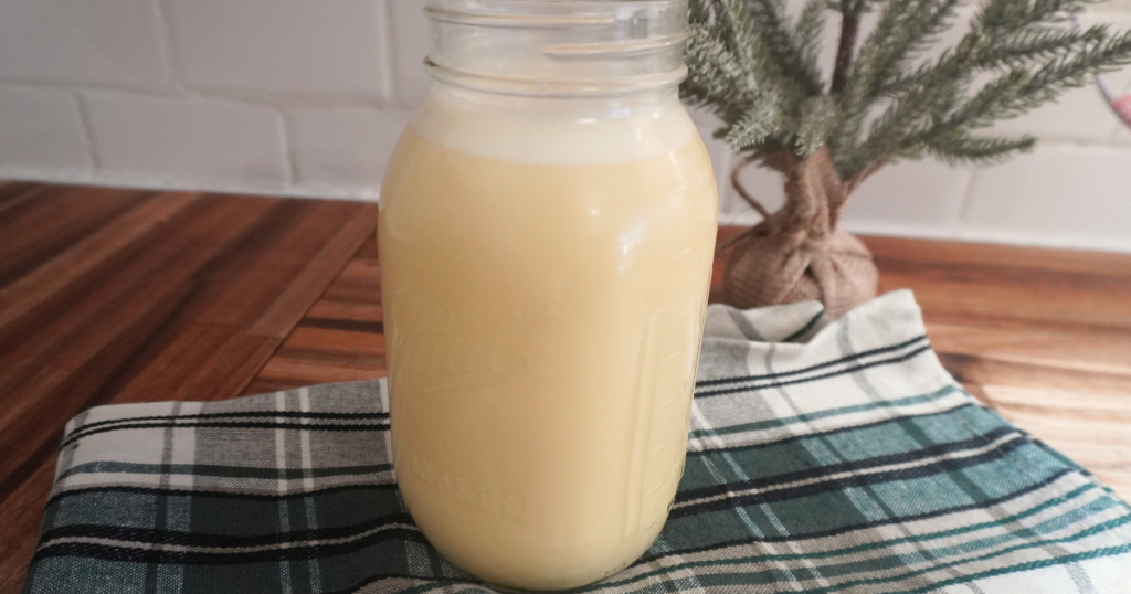 Mason jar full of eggnog on green checkered towel.