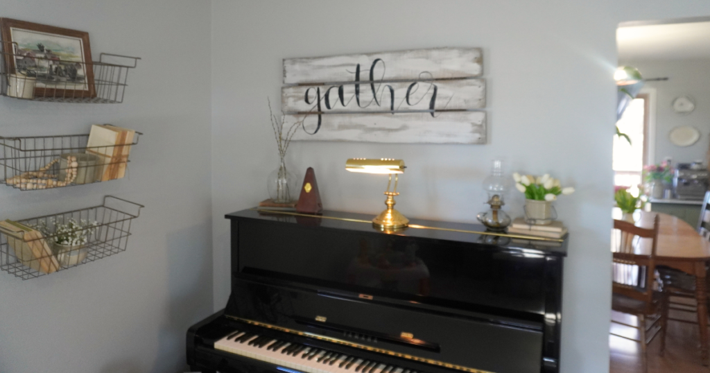 Black piano with tulips and stems on top and three wire baskets with Spring decor hanging on wall.