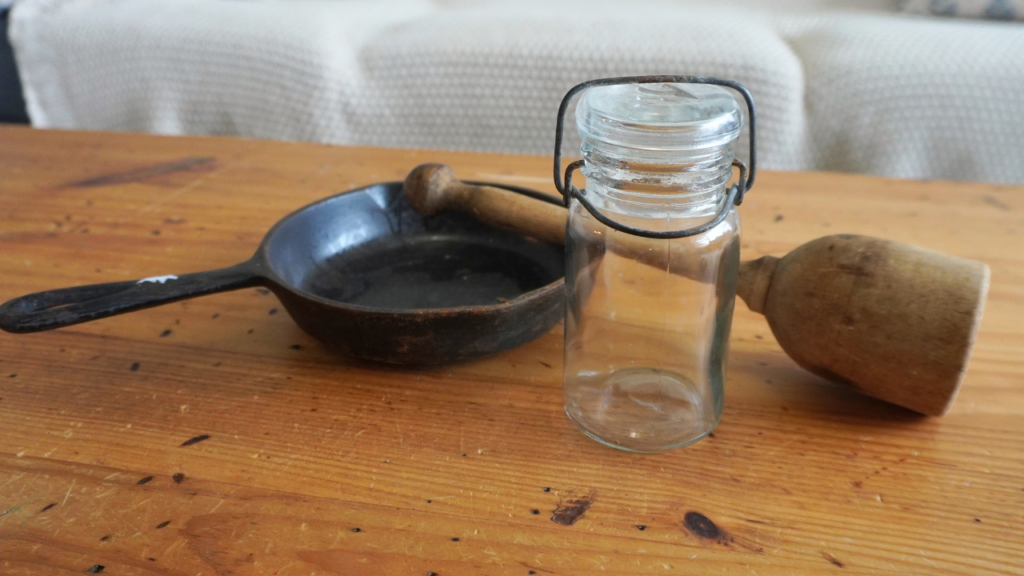 cast iron skillet next to glass jar and wood masher