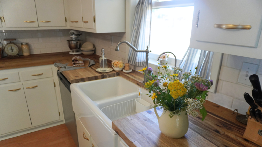 kitchen counter with flowers on one side of sink and bread on the other.