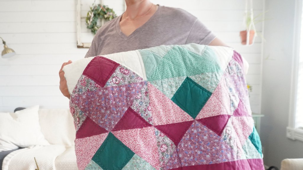 person holding red, maroon, green handmade quilt