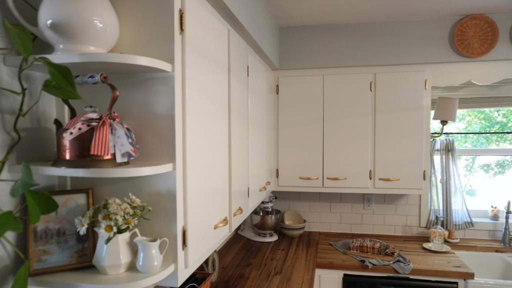 Close up of three shelves with flowers and patriotic decor and counter with loaf of berry bread in background