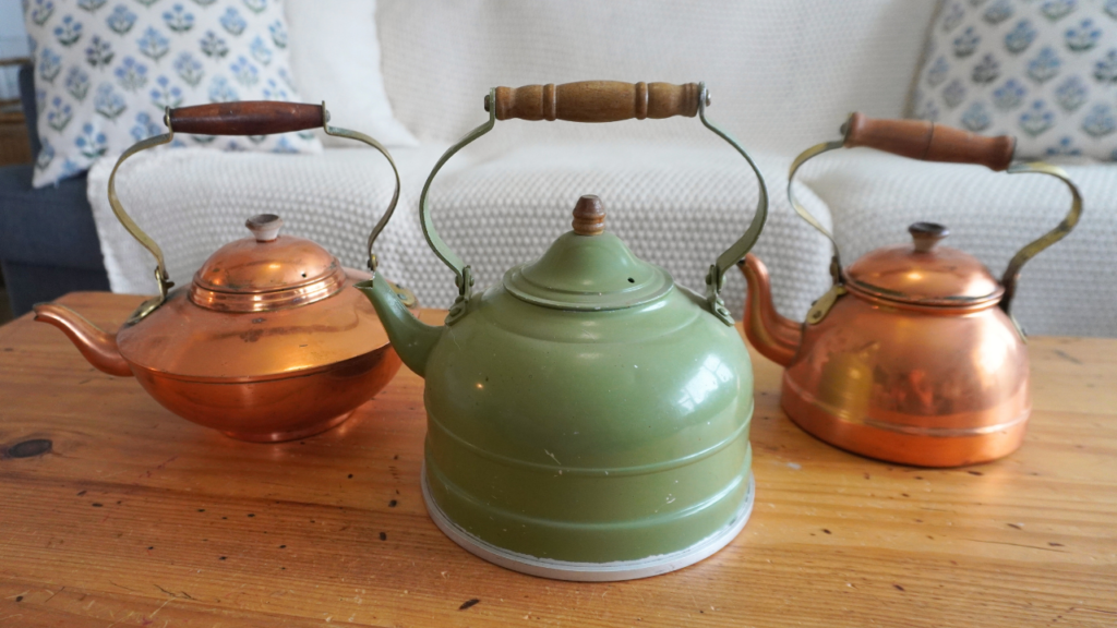 Two copper tea kettles with a green one in middle