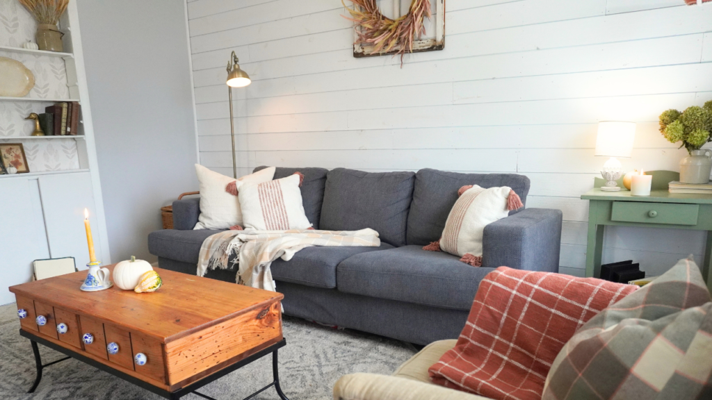Closer view of living room. throw blankets and pillows for Fall, pumpkins on coffee table, candles, wheat stems.