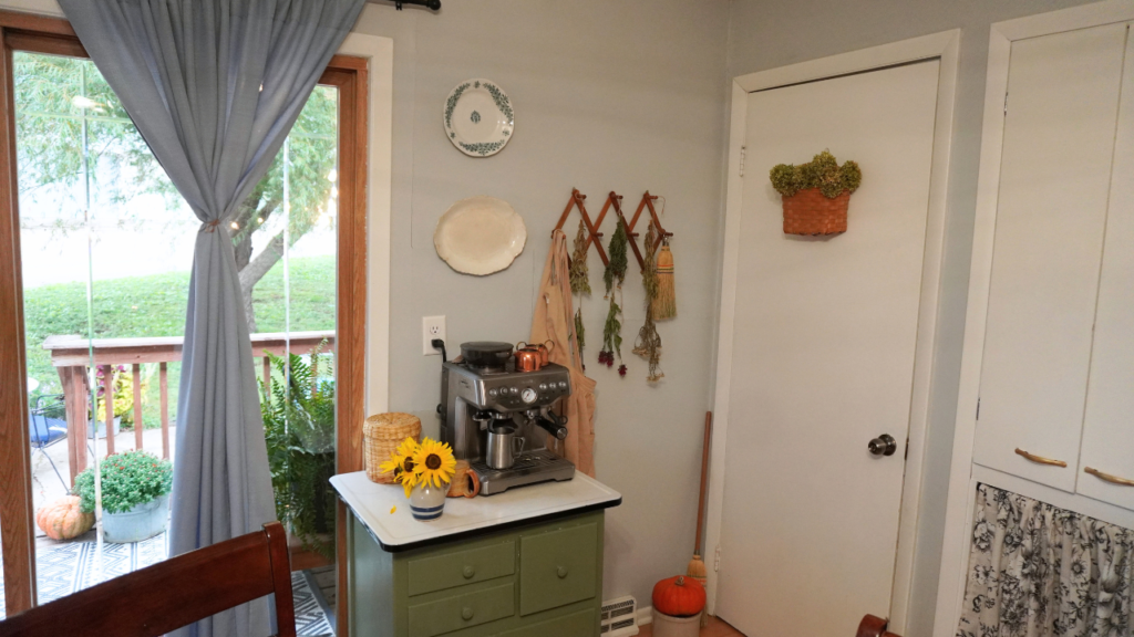 Flowers on wall rack drying, green stand with coffee maker with sunflowers and copper creamer and sugar set.